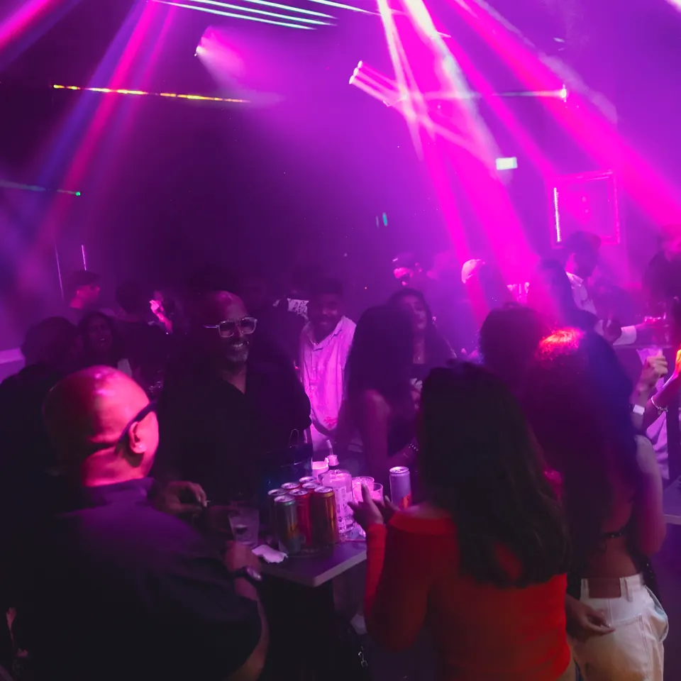 The crowd under pink and violet stage lights on a busy night inside DESTINO